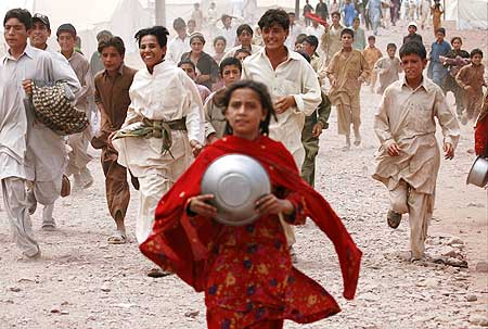 Children, fleeing a military offensive in the Swat valley, chase after food donations at a UN camp