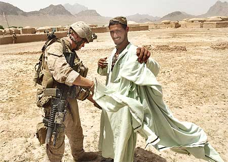 A US Marine searches a man for weapons in a village in Golestan district of Farah province