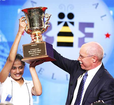 Kavya is presented the winner's trophy by President and CEO of the EW Scripps Company Richard Boehne