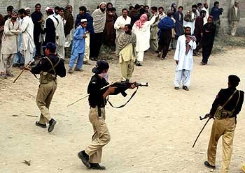 Policemen try to control an unruly crowd in Pakistan.