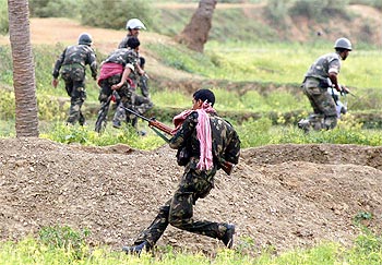 Paramilitary soldiers run for cover during a gunfight with Maoist rebels in Pirrakuli village near Lalgarh