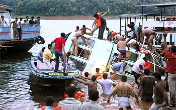 Rescue workers stand over the capsized boat on Periyar lake in Thekkady on Wednesday