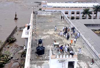 Flood-affected people stand on top of a building in the flooded areas of Mantralaya district of Andhra Pradesh