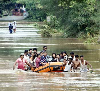 People use a rescue raft as they wade through floodwaters