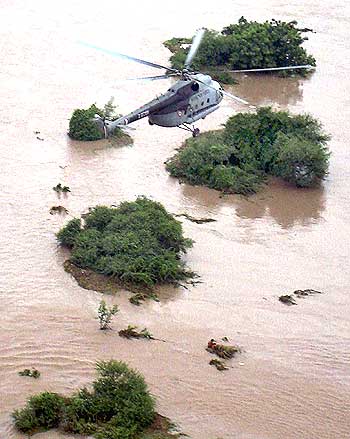 An IAF rescue team member prepares to lift a flood victim from a flooded area