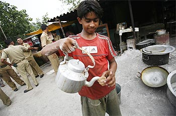 A child labourer serves tea outside a roadside tea-stall