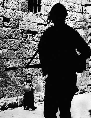 A file photograph from April 15, 1988, shows a Palestinian boy looking at an armed Israeli border policeman in the Old City.