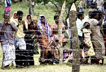 Civilians stand behind the barbed-wire perimeter fence of the Manik Farm refugee camp located on the outskirts of northern Sri Lankan town of Vavuniya.