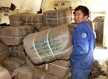A worker with blankets delivered from India as he unloads a plane in Termez, on the Uzbegistan-Afgha