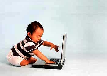 An infant plays with a laptop