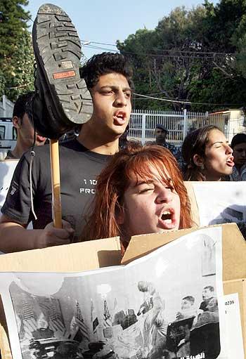 People hold banners and shoes during a protest