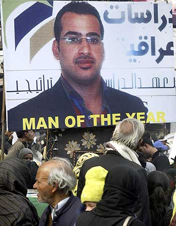People walk past poster of Iraqi journalist al-Zaidi