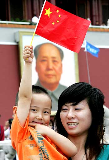 Tourists pose for a picture alongside a Mao portrait close to Tiananmen Square in Beijing