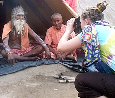 Some sadhus pose for a tourist at the Kumbh Mela