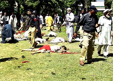 Police and residents stand over victims at the site of the suicide bomb attack