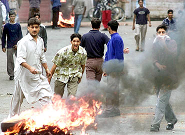 Protesters shout slogans during a clash with police in Srinagar