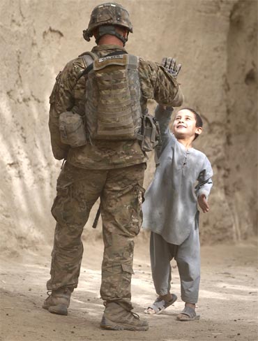 A US trooper high-fives a boy during a patrol through the village of Tabinolye in Arghandab