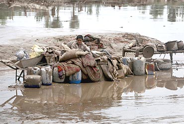 A boy sits next to his belongings while waiting to be evacuated from floods in Nowshera, located in Pakistan's northwest Khyber-Pakhtunkhwa Province, on August 2