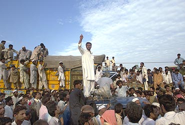 A man requests aid for flood victims amidst passengers and cargo trucks which were halted by townsmen requesting relief supplies in Nowshera on August 2