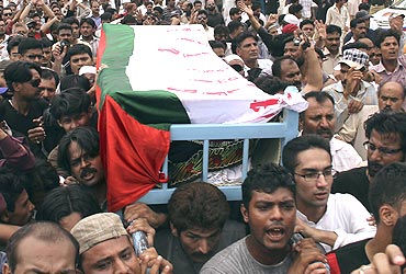 Supporters carry the flag-draped coffin of MQM leader Raza Haider