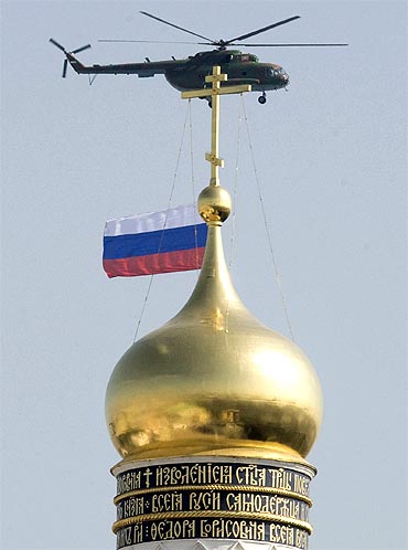 A military helicopter carrying the Russian national flag flies past the Bell Tower of Ivan The Great in the Kremlin