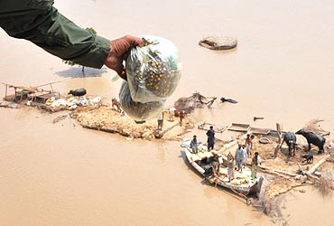 Families marooned by flood waters recieve food from an army helicopter in the Rajanpur district of Pakistan's Punjab province