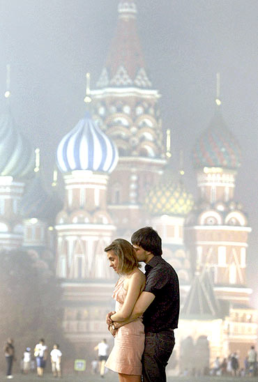 A couple stands in front of the St Basil's Cathedral shrouded in smog in Moscow