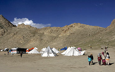 Children, victims of the flash flood, walk past relief tents in Leh