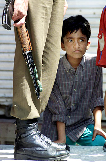 A youngster peers from behind a securityman in Maisuma, Srinagar
