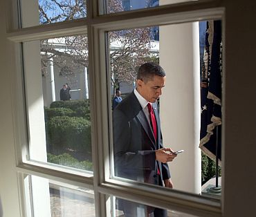 Obama checks his BlackBerry as he walks along the Colonnade to the Oval Office