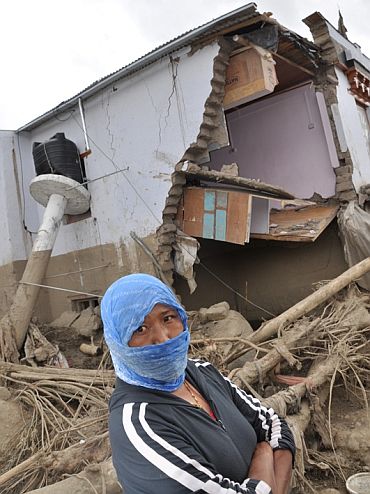 A villager beside her destroyed house