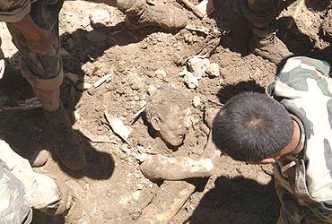 Army personnel extract the body of a young boy from the rubble