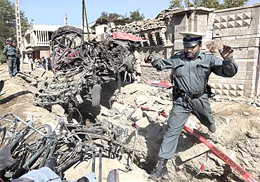 An Afghan policeman jumps over debris at the site of a blast outside the Indian embassy in Kabul