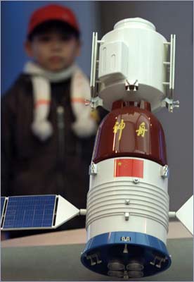 A young boy looks at a model Chinese spaceship displayed at an exhibition center in Shanghai