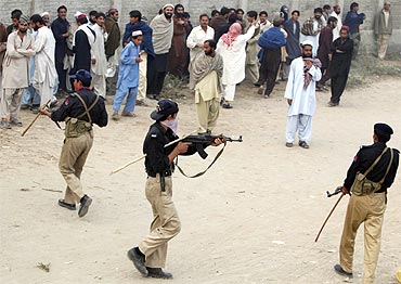 A policeman points a gun at an unruly crowd in Pakistan's South Waziristan province