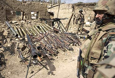 Pakistani soldiers stand next to weapons and ammunition (L) recovered during military operations against Taliban militants in South Waziristan