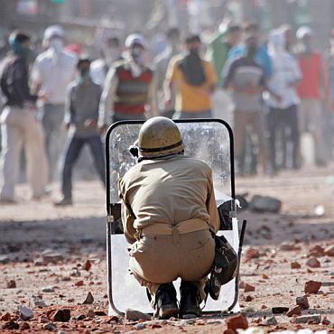 A policeman takes cover as Kashmiri protestors pelt stones