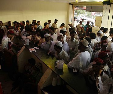 People wait at a counter for their Haleem