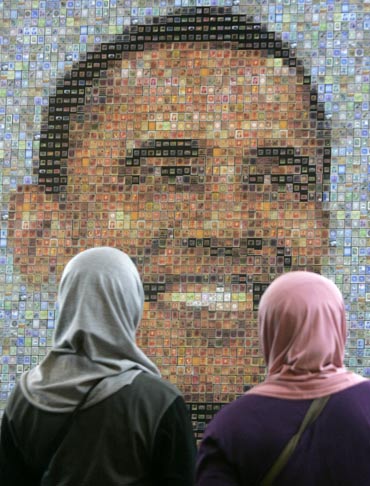 Muslim women look at an image of Barack Obama, made from a mosaic of stamps, in Jakarta