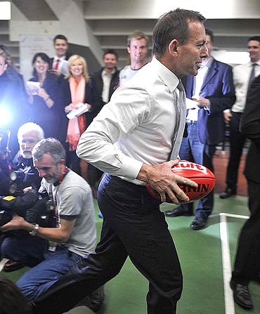 Tony Abbott with an Australian football at the Essendon Football Club
