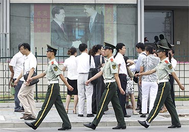 Policemen patrol past a photograph showing China's President Hu Jintao shaking hands with US President Barack Obama