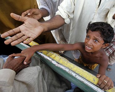 A boy reaches out for relief goods distributed from local residents to flood victims in Muzaffargarh district of Punjab province