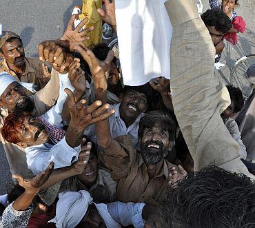 People reach out for relief goods distributed from local residents to flood victims in Muzaffargarh district