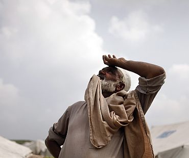 A man looks up as clouds gather over a camp for flood victims near the town of Pir Sabaq in Pakistan's northwest Khyber-Pakhtunkhwa Province