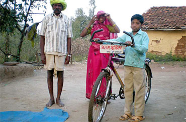 A young village boy prepares to leave for school on his bicycle