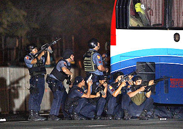 Philippine police take their position during the assault on a bus with tourists being held hostage at Quirino Grandstand in Manila