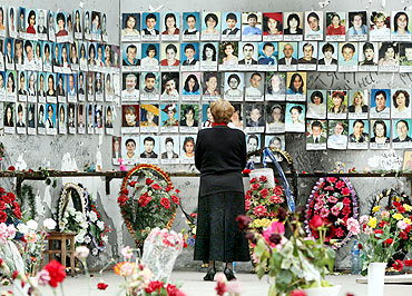A woman grieves at the wall filled with photographs of the siege victims