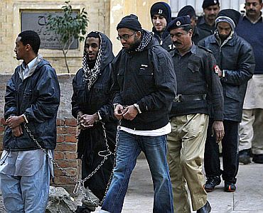 A Pakistani policeman escorts hand-cuffed men identified as Aman Hassan Yemer (left), Ahmed Abdulah Minni (2nd left), Waqar Hussain Khan (right), Ramy Zamzam (left rear), and Umar Farooq (right rear), all American citizens from Northern Virgina, as they leave a police station after their court appearance in Sargodha, Pakistan