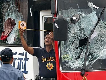 A member of the Philippine National Police (PNP) Scene of the Crime Operations (SOCO) inspects the damage to a tourist bus during their forensic examination