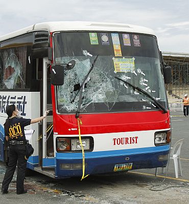 A Scene of the Crime Operations member inspects the damage to the tourist bus